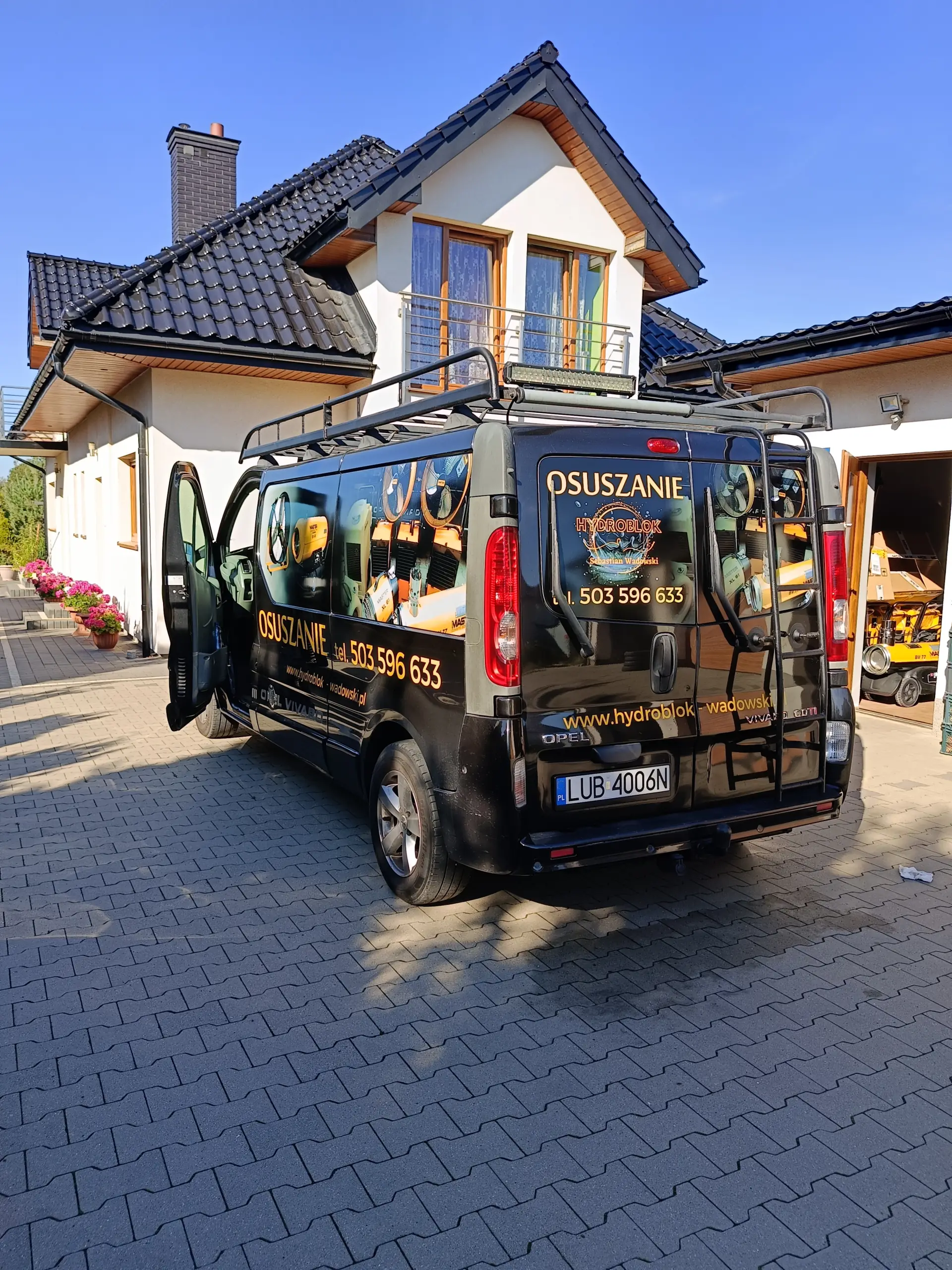Wnętrze firmowego busa HYDROBLOK załadowanego żółtym sprzętem do osuszania.